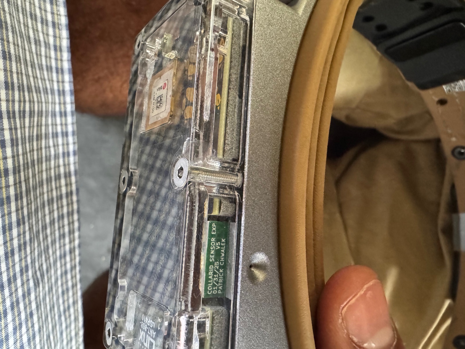 Side view of a collar with a clear cover on an aluminium base, a short crack visible beside a countersunk screw